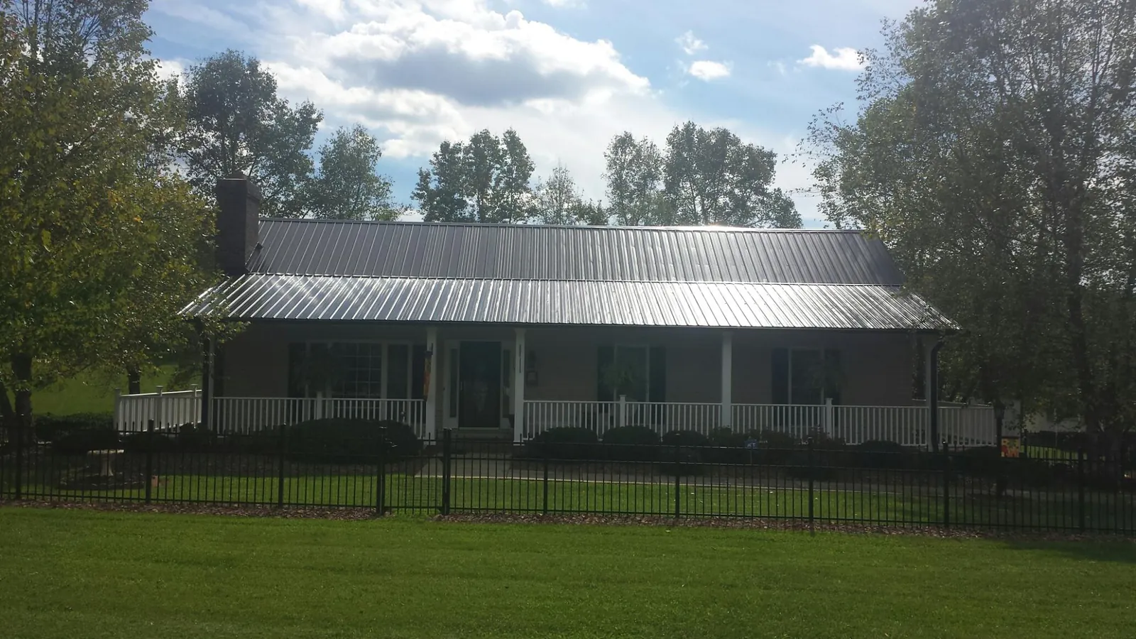 Gray metal roof on a brick ranch with a full width front porch — Gutter Guard Installation work by our crew in Forestville